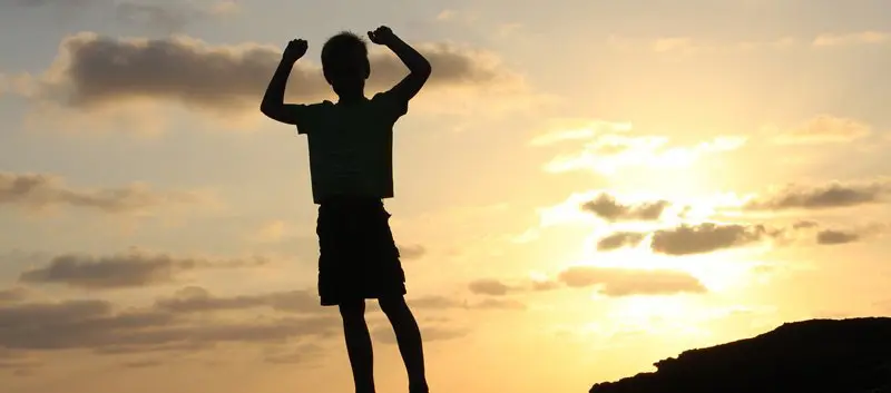 Silhouette of a boy raising his arms in victory.