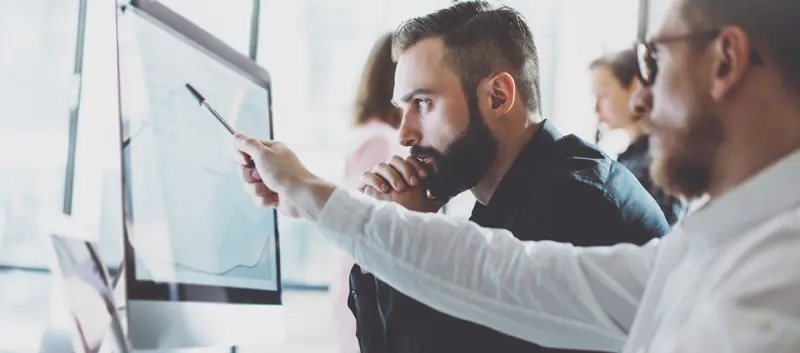Two men looking at a computer monitor.
