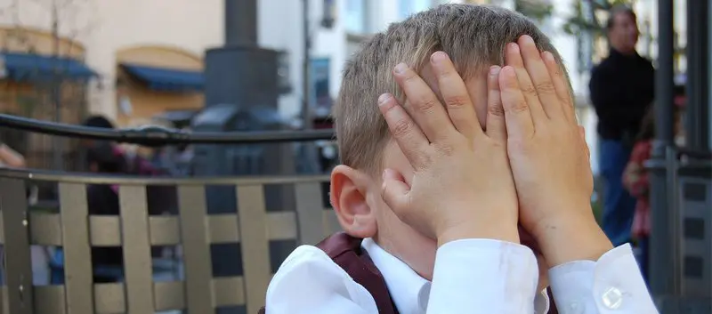 Boy covering his face with his hands.