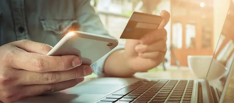 An image of a person holding a bank card and a mobile phone