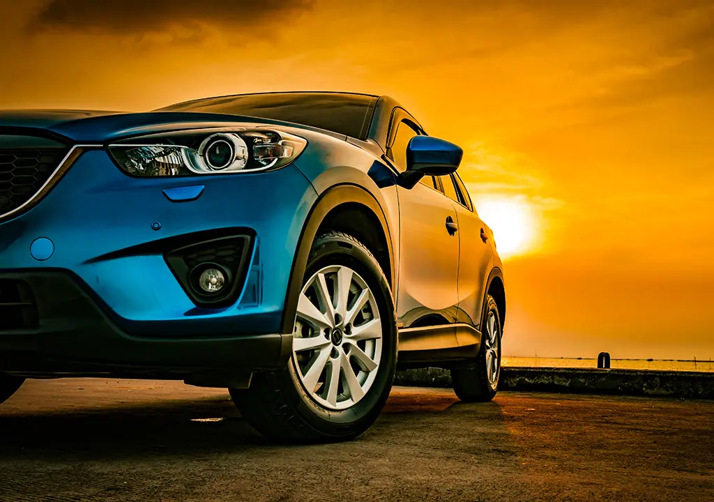 Blue car with a sunset background.