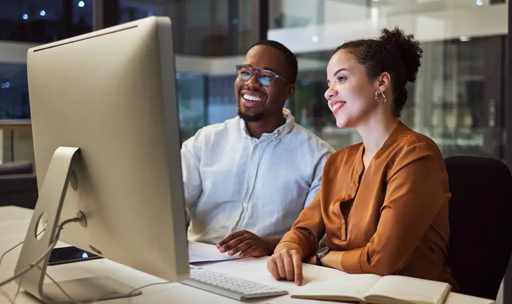 Two people reading a report on a monitor.