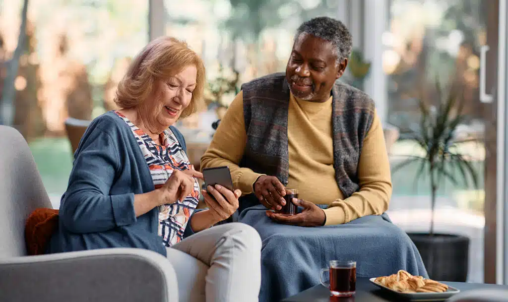 Two care home residents looking at a mobile phone.