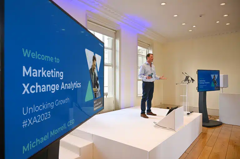 Xchange Analytics 2023. Michael Morrell standing on stage.