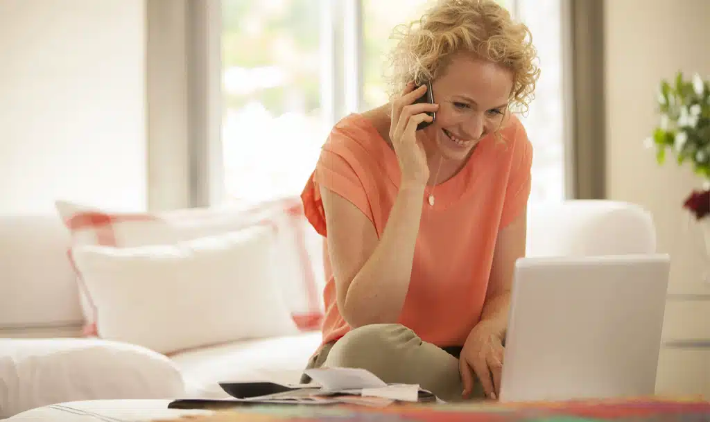 Lady on the phone while looking at her laptop.