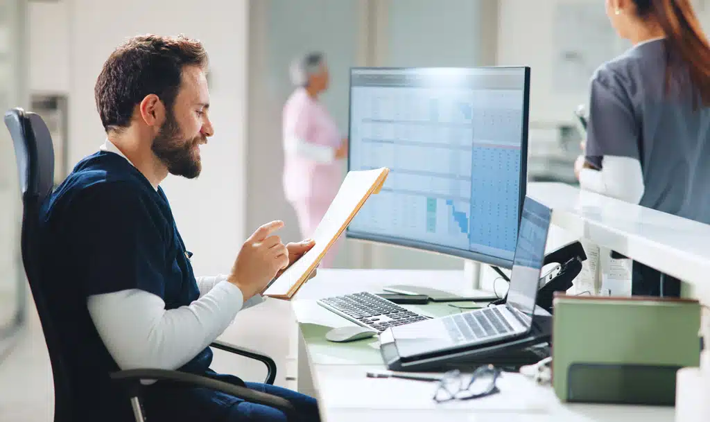 Doctor sitting at a desk reviewing paperwork.