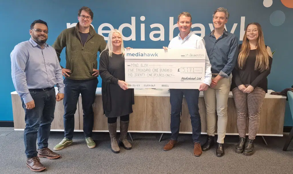 Photo of Mind BLMK and Mediahawk staff holding a cheque from Mediahawk to celebrate fundraising completed in 2025.